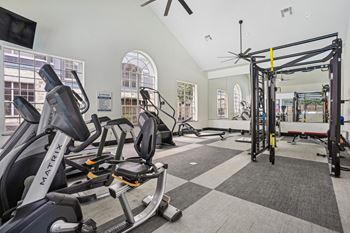 A gym with a variety of equipment including a stationary bike and a pull up bar.